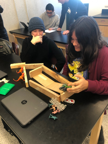 Students using materials in science class to build an energy transfer machine